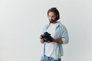 homem hipster fotógrafo dentro uma estúdio em uma branco fundo olhando às a Câmera tela e configuração isto acima para uma foto tiro