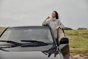 mulher com vermelho cabelo dentro uma suéter perto a carro natureza estilo de vida foto