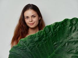 mulher com verde folha em luz fundo limpar \ limpo pele cosmetologia foto