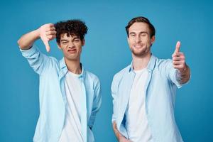 dois amigos dentro idêntico camisas e uma camiseta gesticulando com seus mãos em uma azul fundo foto