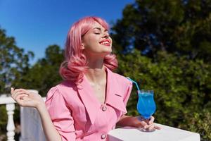 jovem fêmea dentro Rosa vestir ao ar livre com coquetel feliz fêmea relaxante foto