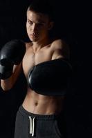 atleta dentro Preto boxe luvas em uma Sombrio fundo fisiculturista ginástica modelo foto