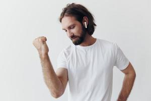 à moda homem dentro uma branco camiseta com sem fio fones de ouvido dentro dele orelhas tendo Diversão ouvindo para música sorrir em uma branco fundo estilo de vida foto