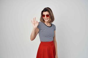 mulher vestindo oculos de sol vermelho saia moda verão posando foto