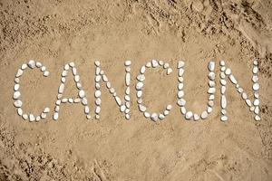 Cancun - palavra fez com pedras em areia foto