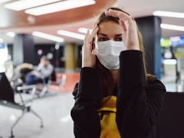 mulher vestindo uma médico mascarar esperando para uma voar aeroporto fadiga foto