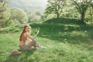 topo Visão do uma mulher com telefone dentro mão freelance aluna tentando para encontrar Internet conexão dentro natureza dentro uma verde verão parque foto