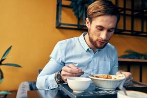 o negócio homem dentro azul camisa tendo almoço às uma cafeteria mesa foto