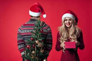 homem e mulher Natal árvore brinquedos presentes feriado vermelho fundo foto