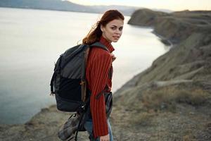 mulher caminhante com uma mochila em dela costas caminhando dentro a montanhas aventura fresco ar foto