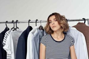 alegre mulher tentando em roupas fazer compras varejo isolado fundo foto