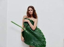 atraente mulher cobre nu corpo com verde folha luz fundo foto