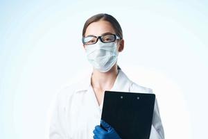 fêmea médico dentro branco casaco médico mascarar documentos laboratório foto