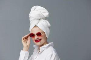 retrato do uma mulher vermelho óculos toalha em cabeça Maquiagem isolado fundo foto