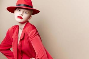 glamouroso mulher vermelho Jaqueta e chapéu vermelho lábios moda bege fundo foto