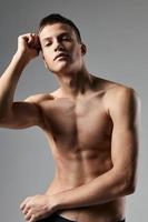 jovem atleta com bombeado acima cubos em dele estômago fisiculturista ginástica tronco modelo cinzento fundo foto