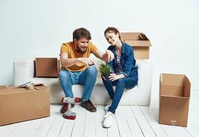 casado casal em uma branco sofá dentro a quarto interior com caixas do comunicação coisas foto