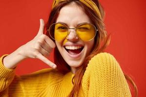 alegre mulher estúdio sorrir emoções amarelo óculos vermelho fundo foto