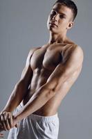 atraente masculino atleta com bombeado acima braço músculos em cinzento fundo cortada Visão foto
