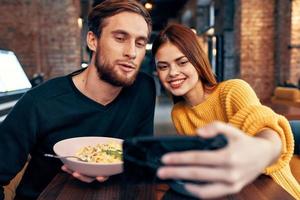 jovem casal dentro uma restaurante faz uma selfie em a telefone comunicação foto