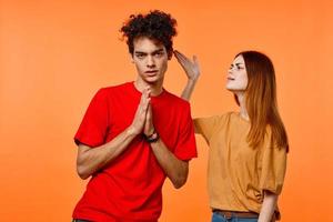 jovem casal dentro multicolorido Camisetas alegria cortada Visão laranja fundo foto