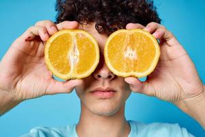 alegre cara segurando laranjas perto dele olhos fechar-se azul fundo foto