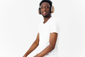 bonito de aparência africana homem vestindo fones de ouvido dentro uma branco camiseta música foto