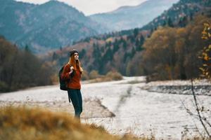 mulher com mochila caminhada de a rio dentro a montanhas panorama foto