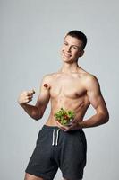 alegre cara com bombeado acima muscular abdômen prato salada dieta Comida isolado fundo foto