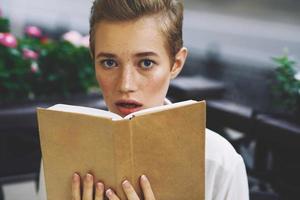 aluna com uma livro dentro dele mãos em a rua período de férias dentro a cidade verão estilo de vida foto