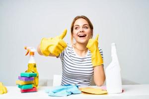 mulher sentado às a mesa borracha luvas limpeza tarefas domésticas detergente serviço foto