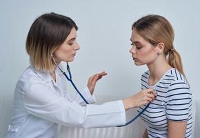 mulher médico com estetoscópio e paciente às a recepção foto