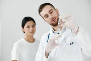 masculino médico com uma seringa dentro dele mão e uma fêmea paciente dentro a fundo vacinação foto