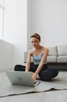 freelance mulher com computador portátil e telefone trabalho a partir de casa sentado em a chão dentro dela casa roupas com uma curto corte de cabelo, livre cópia de espaço foto