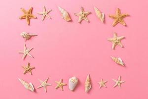 conchas do mar e estrelas do mar em um fundo rosa e areia. conceito de tempo de férias foto