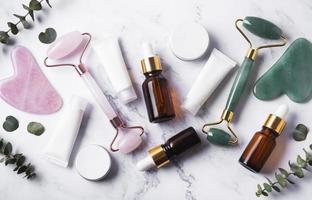 produtos cosméticos, tubos de creme, óleos essenciais e um rolo facial