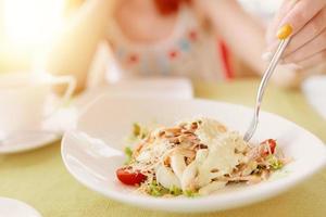 a mão de uma mulher segura o garfo em um prato de salada foto