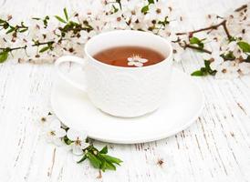 xícara de chá e flores de damasco primavera em um fundo de madeira