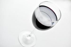 copo grande de vinho tinto em um fundo branco foto