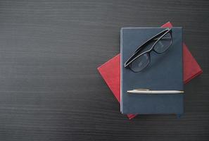 óculos e livro na mesa de madeira foto