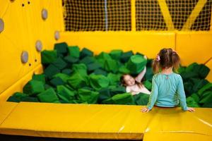 pequeno menina criança mentiras em verde suave cubos às Parque infantil parque. criança dentro ativo entretenimento. foto