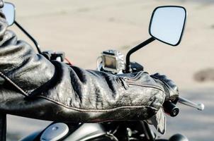mãos de um motociclista em um couro preto em uma bicicleta foto