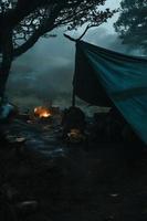 região selvagem sobrevivência. bushcraft barraca debaixo a lona dentro pesado chuva, abraçando a calafrio do alvorecer. uma cena do resistência e resiliência foto