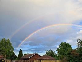 Duplo arco Iris dentro a nublado céu acima a unifamiliar casa dentro a Primavera foto