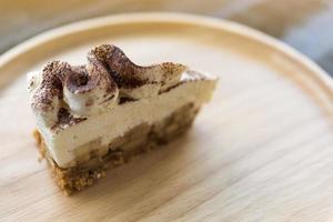 torta de banoffee com chocolate em pó em um prato de madeira foto