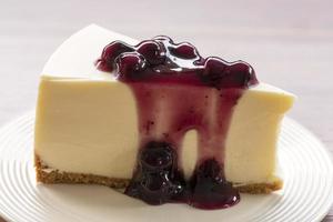 Cheesecake de creme de mirtilo em um prato branco sobre uma mesa de madeira foto