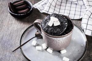 rápido chocolate bolo caneca com marshmallows em uma prato em a mesa foto