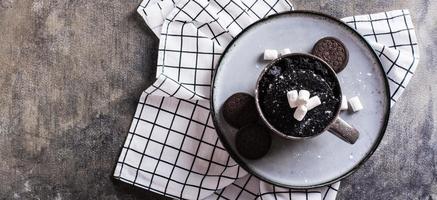 rápido chocolate bolo caneca com marshmallows em uma prato em a mesa topo Visão rede bandeira foto