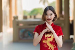 retrato lindo ásia mulher dentro cheongsam vestido, tailândia gente, feliz chinês Novo ano conceito, feliz ásia senhora dentro chinês tradicional vestir segurando uma vermelho envelope foto