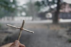 mão segurando uma cruz de Jesus Cristo em uma tumba. símbolo da crença na religião do cristianismo foto